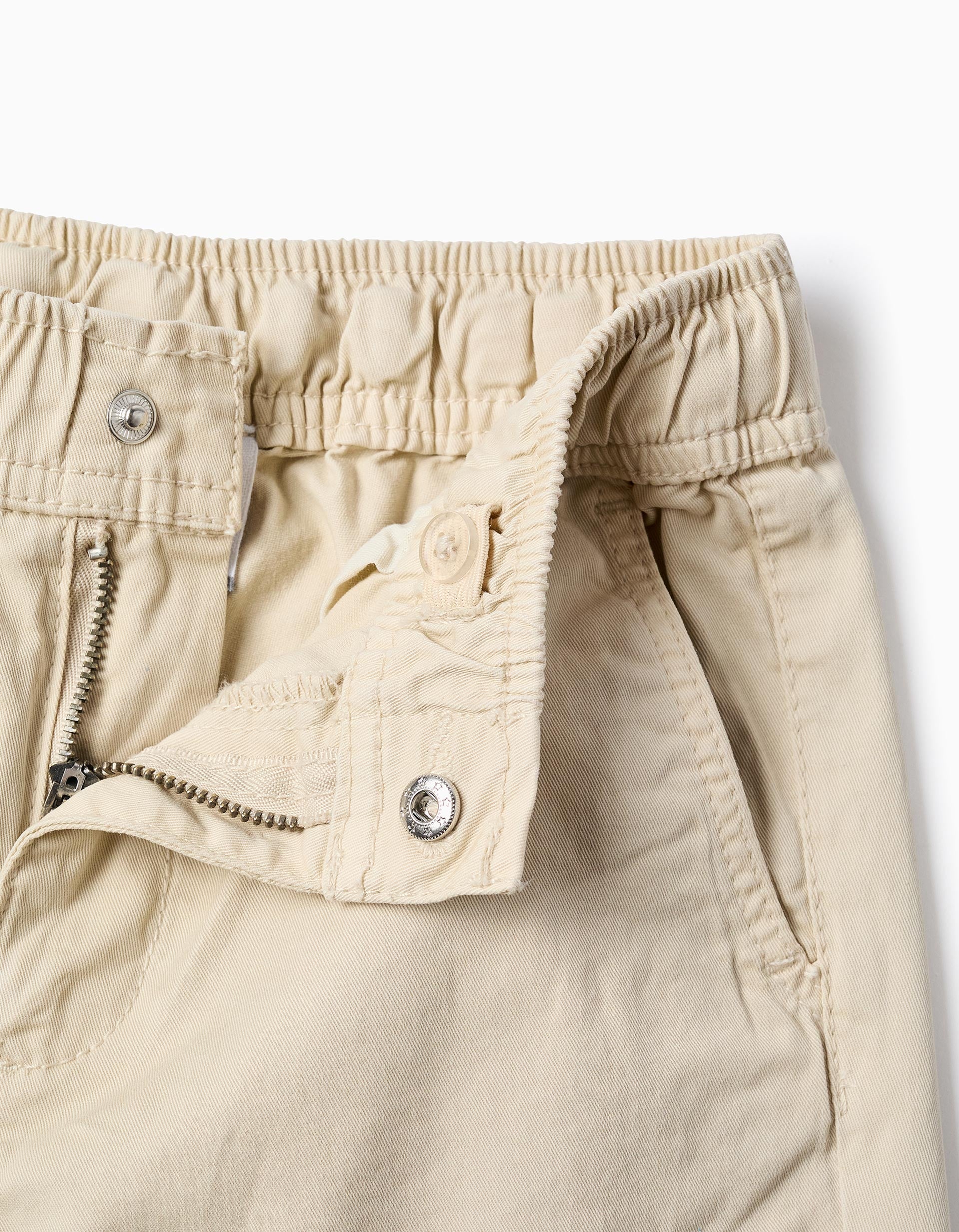 Detalle de cierre y botón en pantalón beige infantil